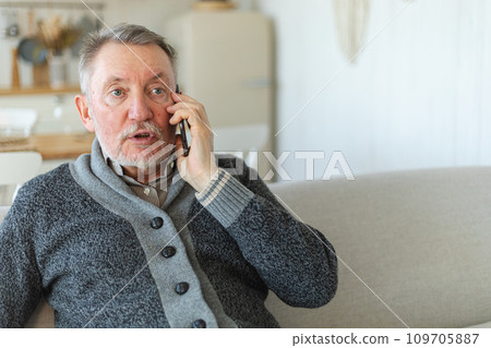 Happy middle aged senior man talking on smartphone with family friends. Older mature grandfather with cell phone talking with grown up children, resting at home. Older generation modern tech usage Happy middle aged senior man talking on smartphone with family friends. Older mature grandfather with cell phone talking with grown up children, resting at home. Older generation modern tech usage 109705887