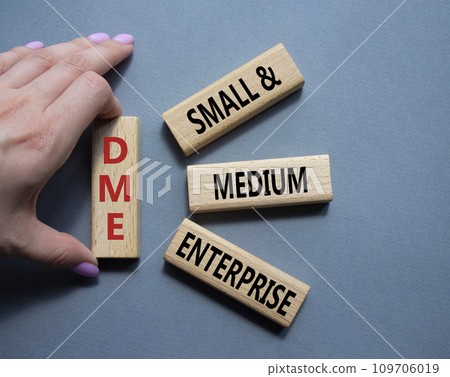 DME - Small and Medium Enterprise symbol. Concept word DME on wooden blocks. Businessman hand. Beautiful grey background. Business and DME concept. Copy space. DME - Small and Medium Enterprise symbol. Concept word DME on wooden blocks. Businessman hand. Beautiful grey background. Business and DME concept. Copy space. 109706019