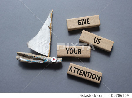 Attention symbol. Concept word Give us your attention on wooden blocks. Beautiful grey background with boat. Business and Give us your attention concept. Copy space 109706109