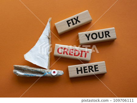 Fix your credit here symbol. Concept words Fix your credit here on wooden blocks. Beautiful orange background with boat. Business and Fix your credit here concept. Copy space. 109706111