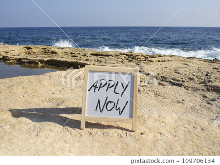 Apply now symbol. Concept word Apply now on white chalk blackboard. Beautiful sea background. Business and Apply now concept. Copy space 109706134