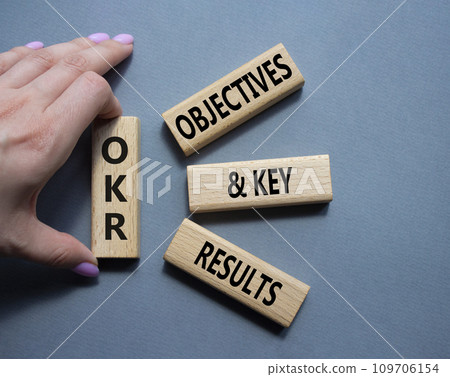 OKR objectives and key results symbol. Wooden blocks with words OKR objectives and key results. Businessman hand. Beautiful grey background. Business and OKR concept. Copy space. OKR objectives and key results symbol. Wooden blocks with words OKR objectives and key results. Businessman hand. Beautiful grey background. Business and OKR concept. Copy space. 109706154