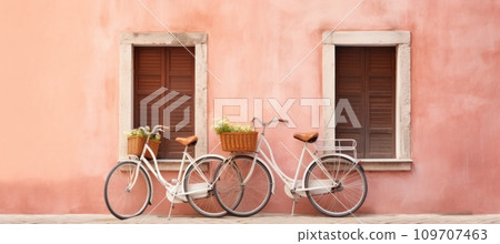 old wooden bicycles by the door of a pink wall 109707463