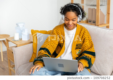 African american girl using laptop at home office looking at screen typing chatting reading writing email. Young woman having virtual meeting online chat video call conference. Work learning from home African american girl using laptop at home office looking at screen typing chatting reading writing email. Young woman having virtual meeting online chat video call conference. Work learning from home 109708252
