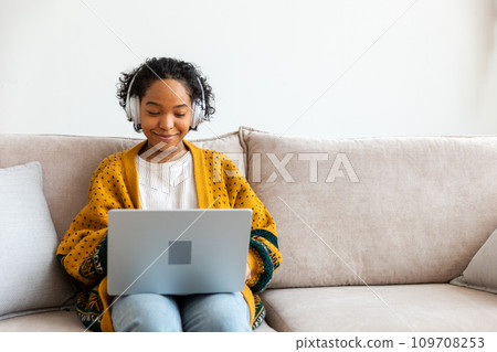 African american girl using laptop at home office looking at screen typing chatting reading writing email. Young woman having virtual meeting online chat video call conference. Work learning from home African american girl using laptop at home office looking at screen typing chatting reading writing email. Young woman having virtual meeting online chat video call conference. Work learning from home 109708253