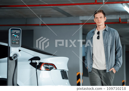 Young man travel with EV electric car to shopping center parking lot innards 109710218