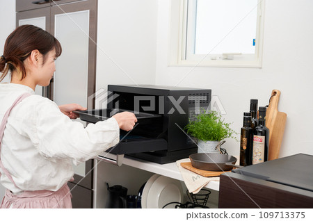 Woman operating a microwave cooking 109713375