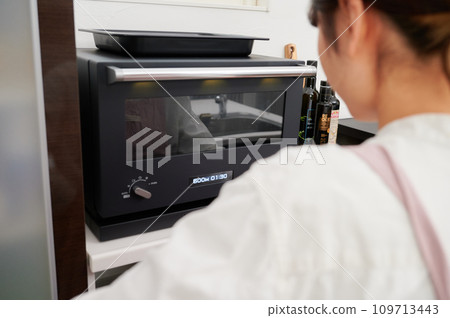 操作微波爐烹調的婦女 109713443