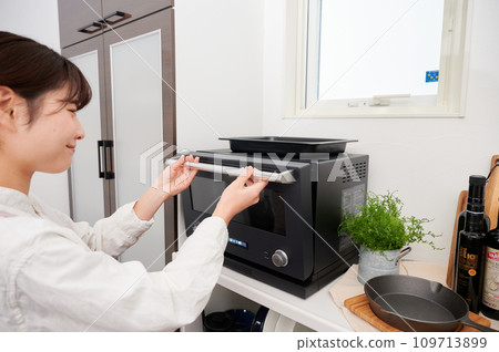 Woman operating a microwave cooking Woman operating a microwave cooking 109713899