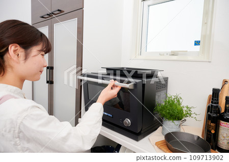 Woman operating a microwave cooking Woman operating a microwave cooking 109713902