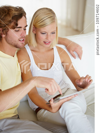 Smile, tablet and young couple on sofa browsing on social media or internet at apartment. Happy, digital technology and man and woman from Australia relax and scroll on website in living room at home 109714602