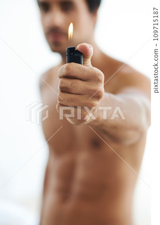 Hand, lighter and fire with a man in studio on a white background for heat or flame closeup. Gas, glow and hot with the body of a shirtless person holding a burning light for orange and warmth Hand, lighter and fire with a man in studio on a white background for heat or flame closeup. Gas, glow and hot with the body of a shirtless person holding a burning light for orange and warmth 109715187