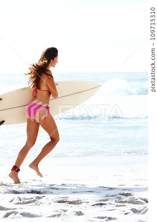 Running, surfboard and woman in bikini at ocean for summer vacation, travel adventure or tropical island. Relax, surfing and girl on blue sky at beach for holiday with waves, sun and sport in Hawaii. 109715310