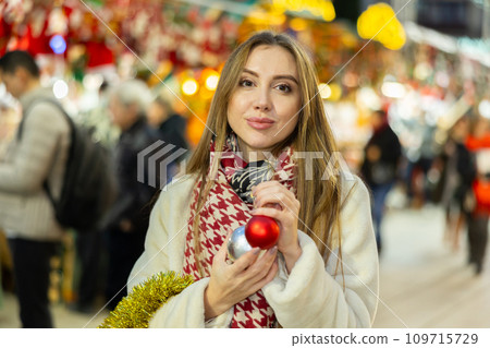 Portrait of dreamily happy girl with Christmas balls in her hands at a street fair in evening Portrait of dreamily happy girl with Christmas balls in her hands at a street fair in evening 109715729