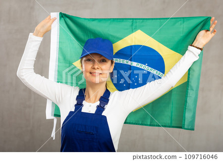 Cheerful female worker with wide grin on her face holding flag of brazil 109716046
