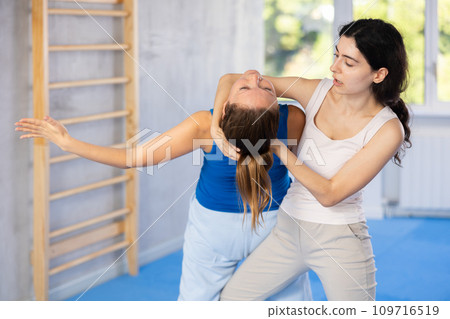Woman makes a choke hold in self defense trainin 109716519