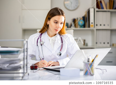 Doctor working at laptop in medical office 109716535