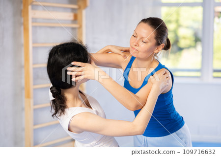 Woman and trainer train painful hold on self-defense course in boxing gym Woman and trainer train painful hold on self-defense course in boxing gym 109716632
