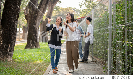 Two Asian female students best friends are enjoying talking while walking, going to school together. 109717038