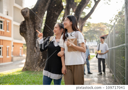 Two cheerful Asian female students friends are enjoying chatting while walking to school together. 109717041