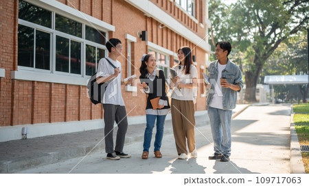 Group of diverse cheerful Asian students friends are enjoying talking while walking in their campus. 109717063