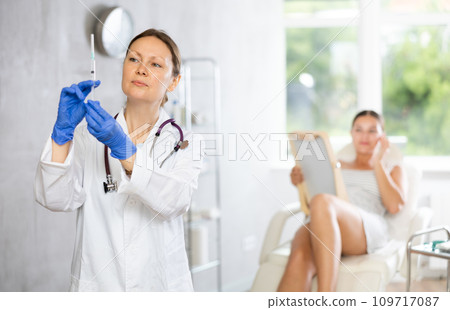 Adult female doctor posing with syringe in medical room 109717087