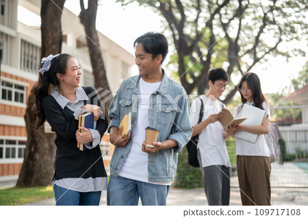 Young cheerful Asian female and male friends are enjoying talking, sharing fun stories outdoors. 109717108