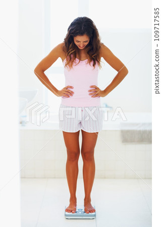 Woman, thinking and scale or weight with diet for healthy body, wellness and nutrition in bathroom at home. Person, results and looking on weighing machine for health, goals or progress in apartment 109717585