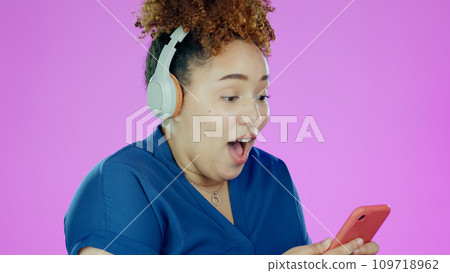 Woman, phone and wow with headphones for winner, promotion or announcement in studio on purple background. Smartphone, person and surprised for notification, sale and lottery news with mock up space Woman, phone and wow with headphones for winner, promotion or announcement in studio on purple background. Smartphone, person and surprised for notification, sale and lottery news with mock up space 109718962