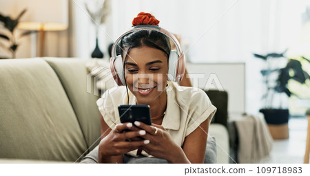 Smartphone, music headphones and happy woman on sofa in home, listening to audio or video app to relax. Phone, sound and Indian person on radio or typing on social media in living room on mobile tech Smartphone, music headphones and happy woman on sofa in home, listening to audio or video app to relax. Phone, sound and Indian person on radio or typing on social media in living room on mobile tech 109718983