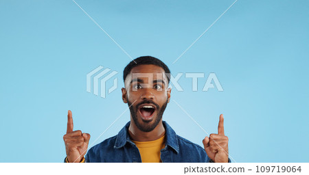 Happy man, pointing and news announcement with portrait in studio, surprise emoji and advertising. Mockup, mexican person and smiling in casual fashion for offer and notification by blue background Happy man, pointing and news announcement with portrait in studio, surprise emoji and advertising. Mockup, mexican person and smiling in casual fashion for offer and notification by blue background 109719064