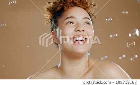 Happy woman, bubbles and skin for beauty, happy with natural cosmetics and glow on brown background. Dermatology, wellness with skincare and liquid soap for self care and anti aging in studio 109719167