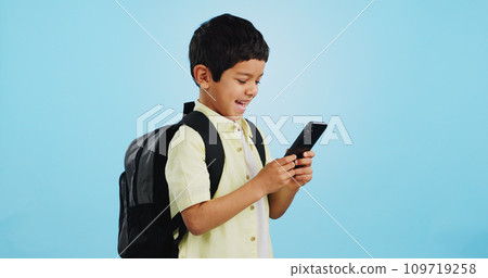School, phone or kid on social media in studio typing to chat, play mobile games or download app. Blue background, student or happy boy child reading notification for online education or tech search 109719258