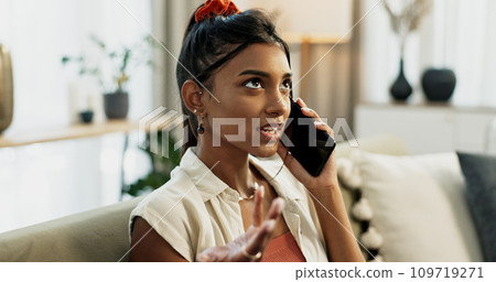 Phone call, fighting and young woman on a sofa for communication in the living room of apartment. Argument, annoyed and Indian female person on mobile conversation with cellphone in lounge at home. 109719271