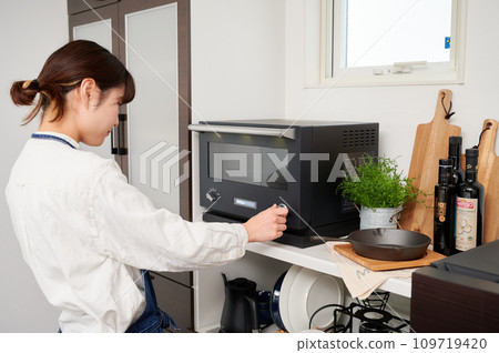 Woman operating a microwave cooking Woman operating a microwave cooking 109719420