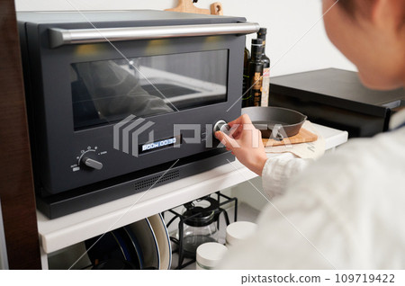 Woman operating a microwave cooking 109719422