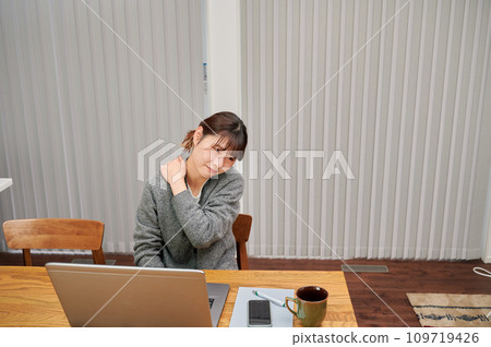Woman with stiff shoulders from desk work, tired, working from home Woman with stiff shoulders from desk work, tired, working from home 109719426