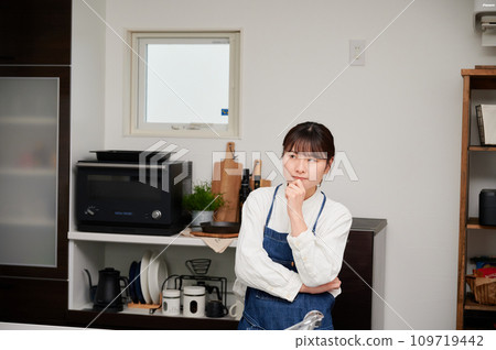 A woman worried in the kitchen thinks 109719442