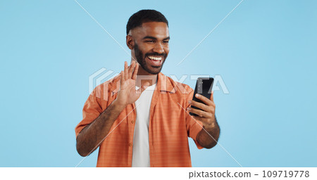 Video call, wave and man with a smartphone, showing and conversation on a blue studio background. Person, speaking and model with a cellphone, online chat and communication with network or connection 109719778