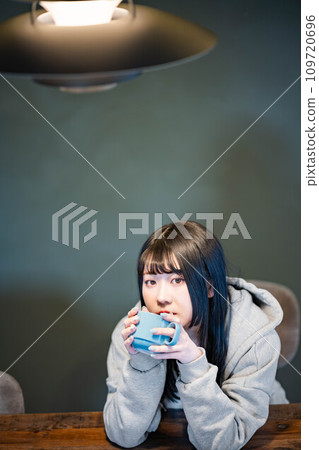 Woman drinking coffee at the dining table 109720696