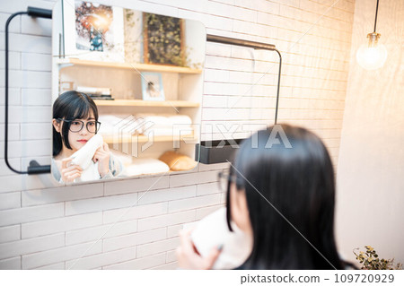 A woman getting ready in the morning in front of the mirror 109720929