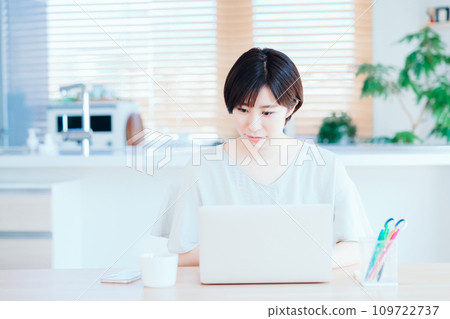 A woman operating a laptop in the living room. A woman operating a laptop in the living room. 109722737