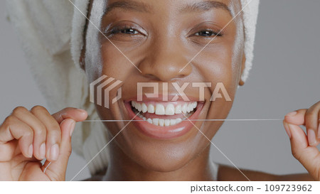 Portrait, black woman with floss for teeth and dental, health and wellness with beauty on grey background. Oral hygiene, orthodontics and clean plaque away with smile and morning routine in studio Portrait, black woman with floss for teeth and dental, health and wellness with beauty on grey background. Oral hygiene, orthodontics and clean plaque away with smile and morning routine in studio 109723962