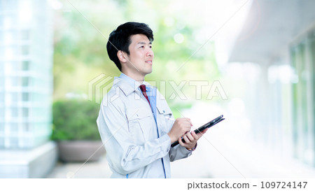A man in work clothes writing on a tablet 109724147