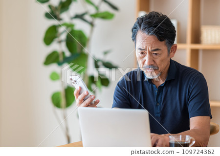 一位老人在他的客廳投資股票。 109724362