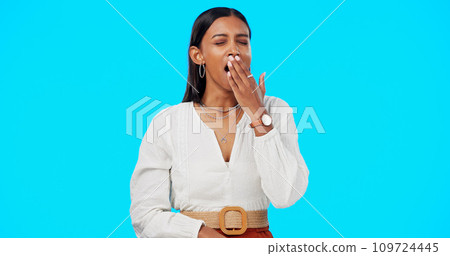 Woman, yawn and hand on mouth, tired and studio by blue background, alone or isolated. Overworked person, burnout and low energy for deadlines, exhausted and fatigue or lazy for nap, sleep and rest 109724445