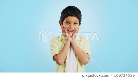 Excited, kid and hands on face for surprise in studio isolated on a blue background mockup space. Portrait, wow and happy child shocked at good news, information announcement and facial expression. Excited, kid and hands on face for surprise in studio isolated on a blue background mockup space. Portrait, wow and happy child shocked at good news, information announcement and facial expression. 109724559
