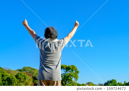 Senior woman walking against the blue sky, Fresh Green Park, diet, exercise, healthy habits, walk, fist pump 109724672