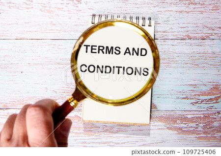 TERMS AND CONDITIONS text seen through magnifying glasses on a notepad 109725406