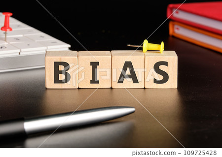 Bias the text of non-wooden cubes next to notepads, a calculator, a pen on a black background 109725428